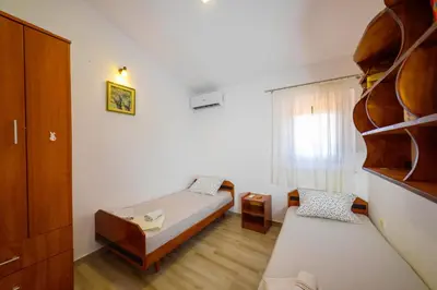 a bedroom with two beds and a book shelf at Apartmani Popović in Popovići