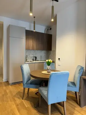 a kitchen and dining room with a wooden table and blue chairs at Cozy sea view apt with garage in Budva