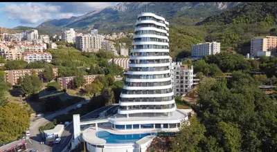 a building with a pool in front of a city at Cozy sea view apt with garage in Budva