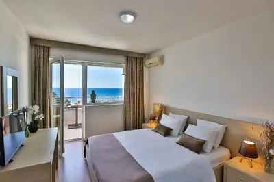 a bedroom with a bed and a balcony with the ocean at Villa Vanty in Sveti Stefan