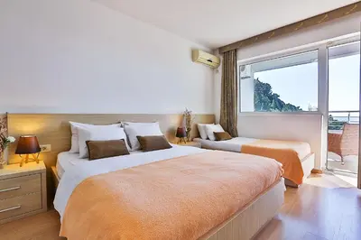 a bedroom with two beds and a large window at Villa Vanty in Sveti Stefan