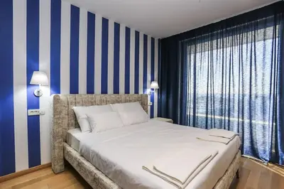 a bedroom with a large bed with blue and white stripes at Status-M Apartments WOW in Budva