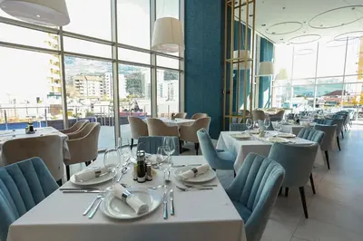 a restaurant with white tables and chairs and windows at Status-M Apartments WOW in Budva
