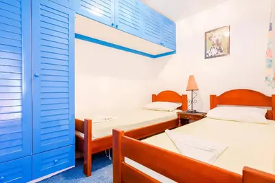 a bedroom with two beds and a blue door at Apartment More - Konoba More in Pržno