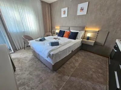 a bedroom with a large bed with blue and orange pillows at AGAPE Apartment in Podgorica