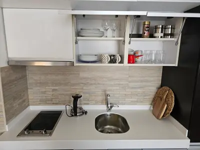 a kitchen counter with a sink and white cabinets at AGAPE Apartment in Podgorica