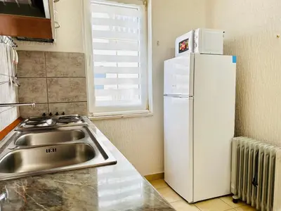 a kitchen with a sink and a white refrigerator at SweetHome in Sutomore