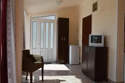 a living room with a television and a chair and a door at Smokva in Bar