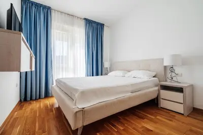 a bedroom with a large bed and blue curtains at Status-M Apartments 153 in Becici