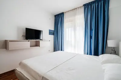 a bedroom with a bed with blue curtains and a television at Status-M Apartments 153 in Becici