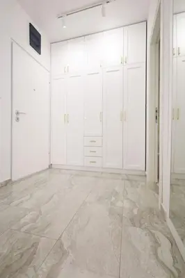 an empty room with white cabinets and marble floors at Status-M Apartments Aura in Becici