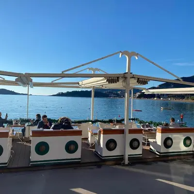 people sitting at tables on a boat near the water at Status-M Apartments Aura in Becici
