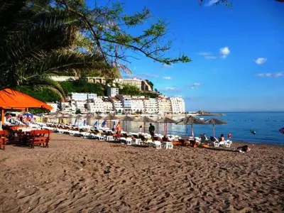 a beach with chairs and umbrellas and the ocean at Status-M Apartments Aura in Becici