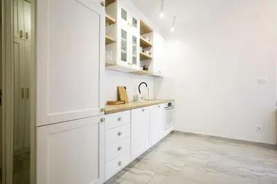 a white kitchen with white cabinets and a tile floor at Status-M Apartments Aura in Becici