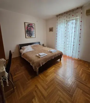 a bedroom with a bed and a wooden floor at Laki Apartment in Podgorica