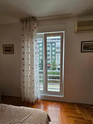 a bedroom with a bed and a large window at Laki Apartment in Podgorica