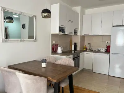 a kitchen with a wooden table and white cabinets at Budva City De Lux in Budva