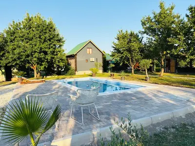 a swimming pool with two chairs next to a house at Tiny house 2 - Imanje Terzic in Podgorica