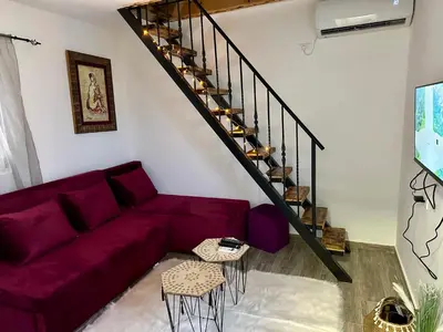 a living room with a purple couch and stairs at Tiny house 2 - Imanje Terzic in Podgorica