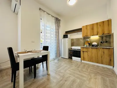 a kitchen with a table and chairs and a refrigerator at Queen of the Beach in Bar