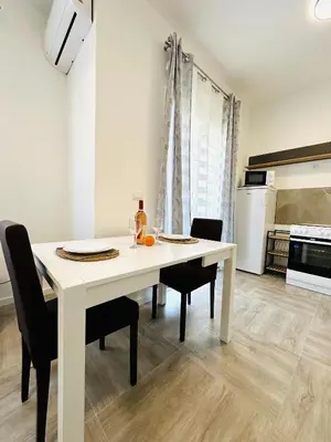 a white dining room table with chairs and a kitchen at Queen of the Beach in Bar