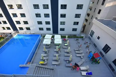 a group of people sitting in chairs next to a swimming pool at Brand New ! Seaside Apt with Poolview & Parking in Budva