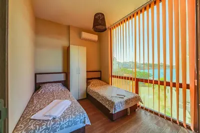two beds in a room with a large window at PETROVIĆ in Bar