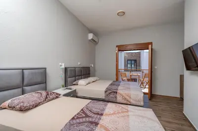 a bedroom with two beds and a balcony at PETROVIĆ in Bar