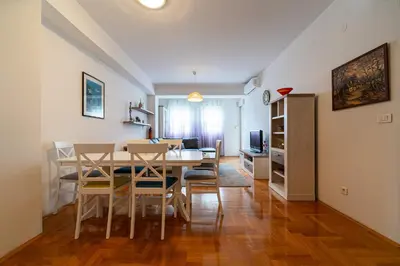 a dining room and living room with a table and chairs at Spacious two bedroom in Podgorica