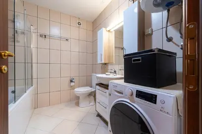 a bathroom with a washing machine and a toilet at Spacious two bedroom in Podgorica