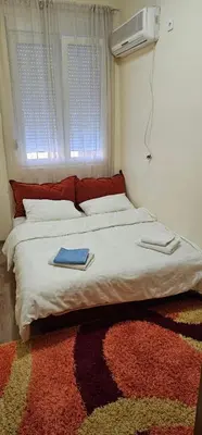 a bedroom with a white bed with a rug at Plaza Centar Podgorica in Podgorica