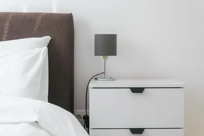 a bed with a table with a lamp on it at One-Bedroom Apartment in the Center of Budva on a Quiet Street 5 Minutes to the Beach in Budva