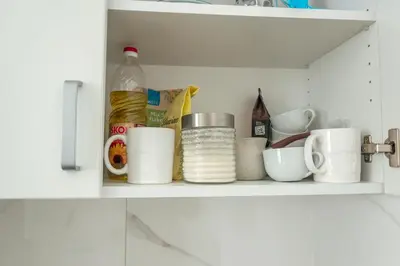 a kitchen shelf with cups and other kitchen items at One-Bedroom Apartment in the Center of Budva on a Quiet Street 5 Minutes to the Beach in Budva