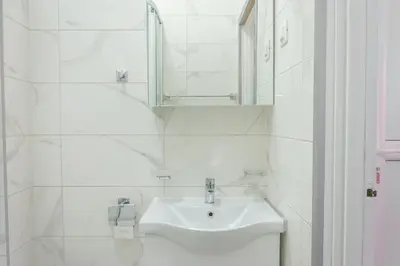 a white bathroom with a sink and a mirror at One-Bedroom Apartment in the Center of Budva on a Quiet Street 5 Minutes to the Beach in Budva
