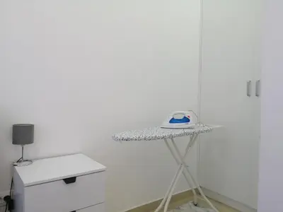 a white room with a shelf with a iron on it at One-Bedroom Apartment in the Center of Budva on a Quiet Street 5 Minutes to the Beach in Budva