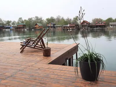 a wooden dock with a chair and houses on the water at NuA House 