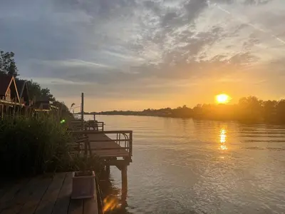 a sunset over a body of water with a dock at NuA House 