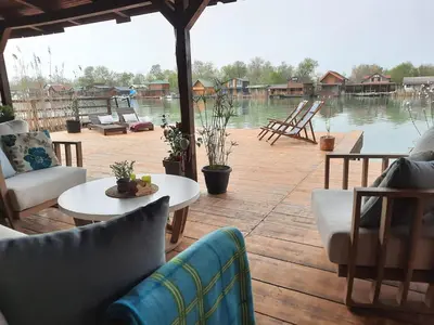 a patio with chairs and tables and a view of the water at NuA House 