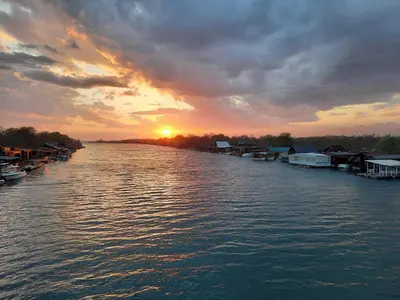 a sunset on a river with boats in the water at NuA House 