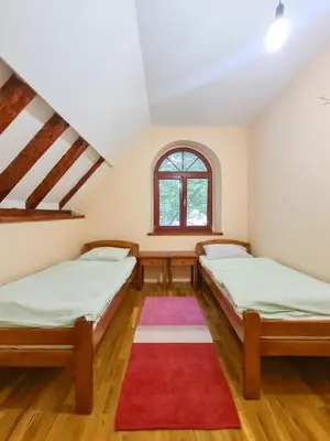 two beds in a room with a red rug at Lovćen Escape, Rustric House in Cetinje