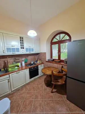 a kitchen with white cabinets and a table and a refrigerator at Lovćen Escape, Rustric House in Cetinje