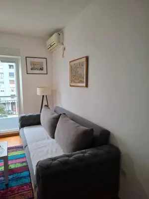 a living room with a couch and a window at Dina's Place in Podgorica