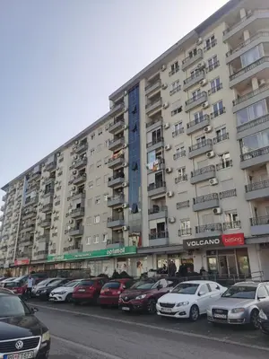 a large building with cars parked in a parking lot at Dina's Place in Podgorica