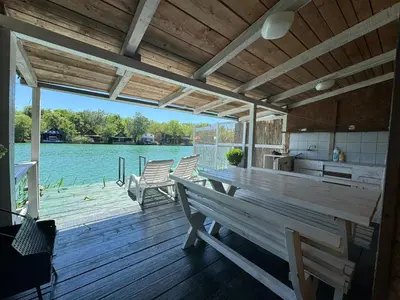 a wooden deck with benches and a kitchen and water at Jungle 1 House Ada Bojana in Ulcinj
