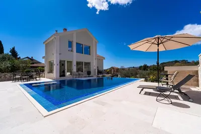 a villa with a swimming pool and an umbrella at Majestic Apartment in Tivat