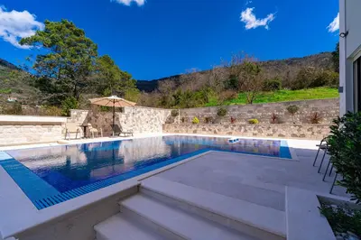 a swimming pool with stairs next to a house at Majestic Apartment in Tivat