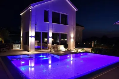 a house with a swimming pool at night at Majestic Apartment in Tivat