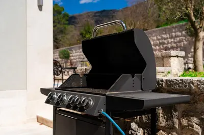 a black barbecue grill sitting next to a wall at Majestic Apartment in Tivat