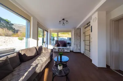 a living room with a couch and a large window at Majestic Apartment in Tivat