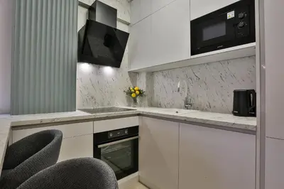 a kitchen with white cabinets and black appliances at Apartments Centar Montesun in Budva